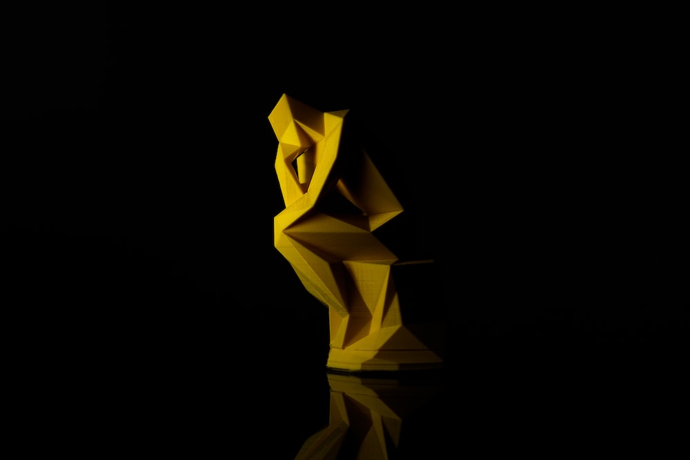 Yellow origami version of the The Thinker statue
